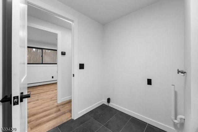 clothes washing area with dark tile patterned flooring and a baseboard radiator