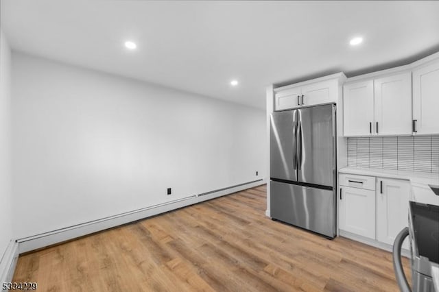 kitchen featuring tasteful backsplash, a baseboard radiator, white cabinets, and stainless steel refrigerator