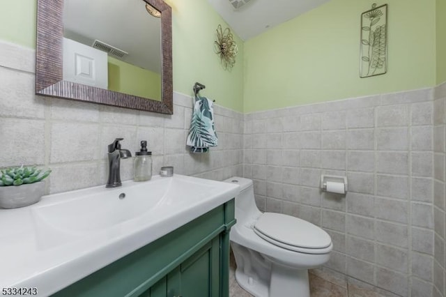 bathroom featuring vanity, tile walls, and toilet