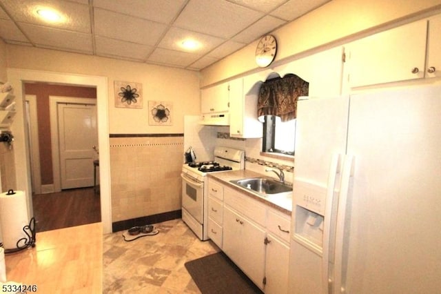 kitchen with white cabinetry, sink, tile walls, exhaust hood, and white appliances