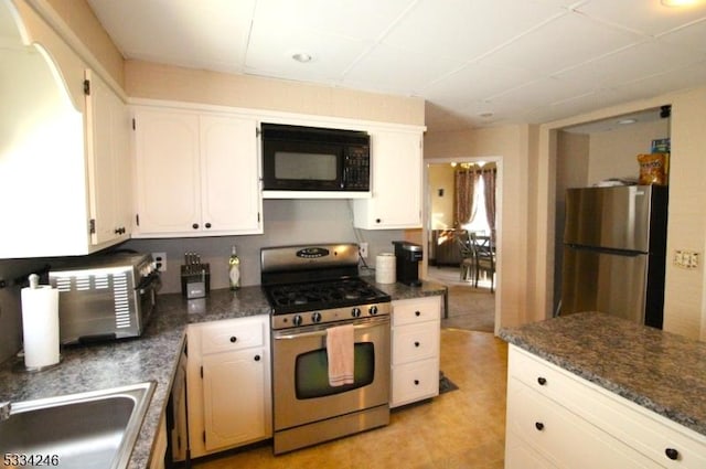 kitchen featuring stainless steel appliances, white cabinetry, sink, and a drop ceiling