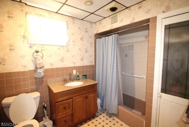 full bathroom with shower / bath combo, tile walls, vanity, and toilet