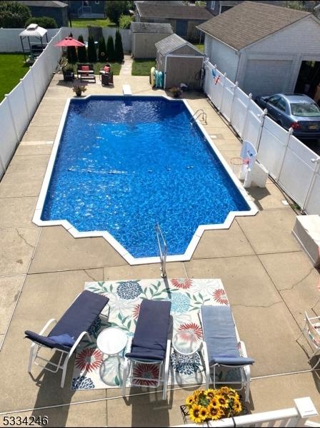 view of swimming pool featuring a patio and a shed