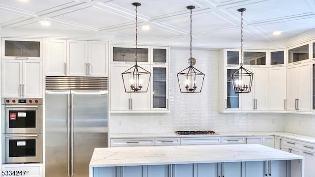 kitchen featuring light stone countertops, appliances with stainless steel finishes, a center island, and decorative light fixtures