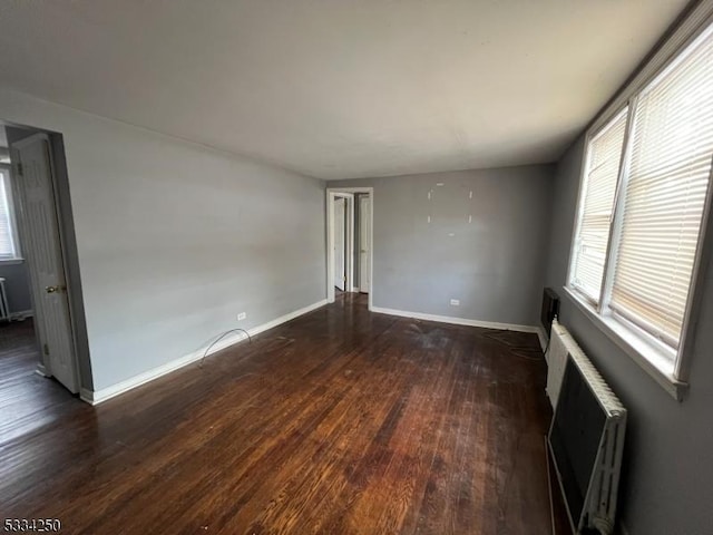 spare room featuring radiator and dark hardwood / wood-style flooring