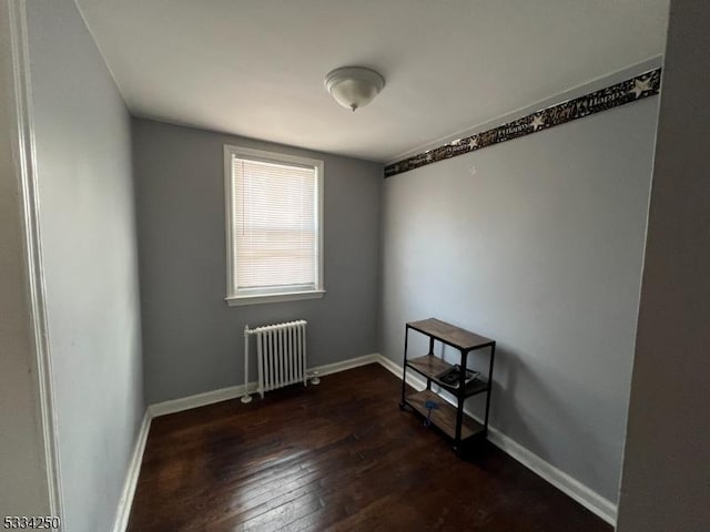 spare room with radiator heating unit and dark hardwood / wood-style floors