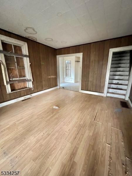 spare room with light wood-type flooring and wood walls