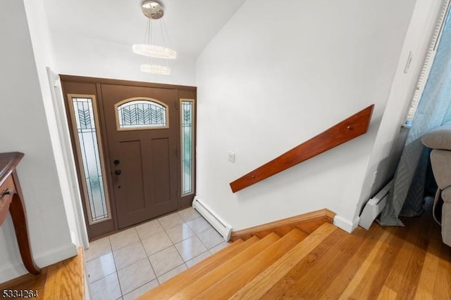 tiled foyer entrance with a notable chandelier and baseboard heating