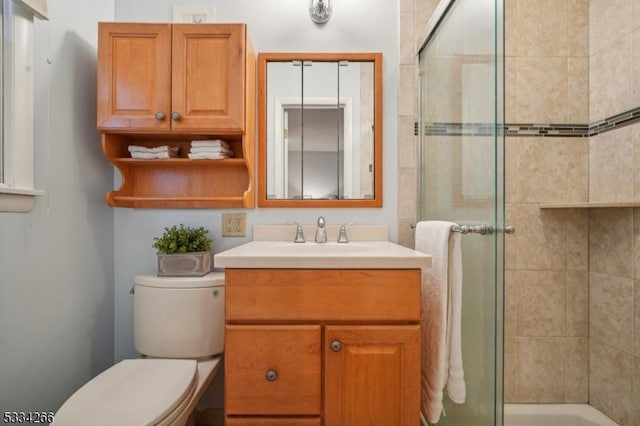 bathroom with vanity, toilet, and a shower with shower door