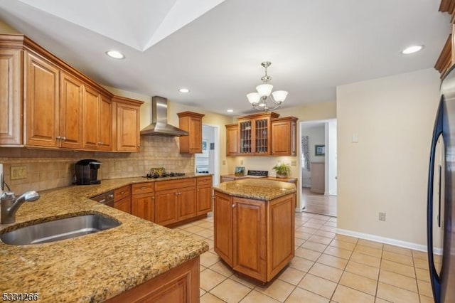 kitchen featuring wall chimney range hood, sink, light tile patterned floors, black appliances, and decorative light fixtures