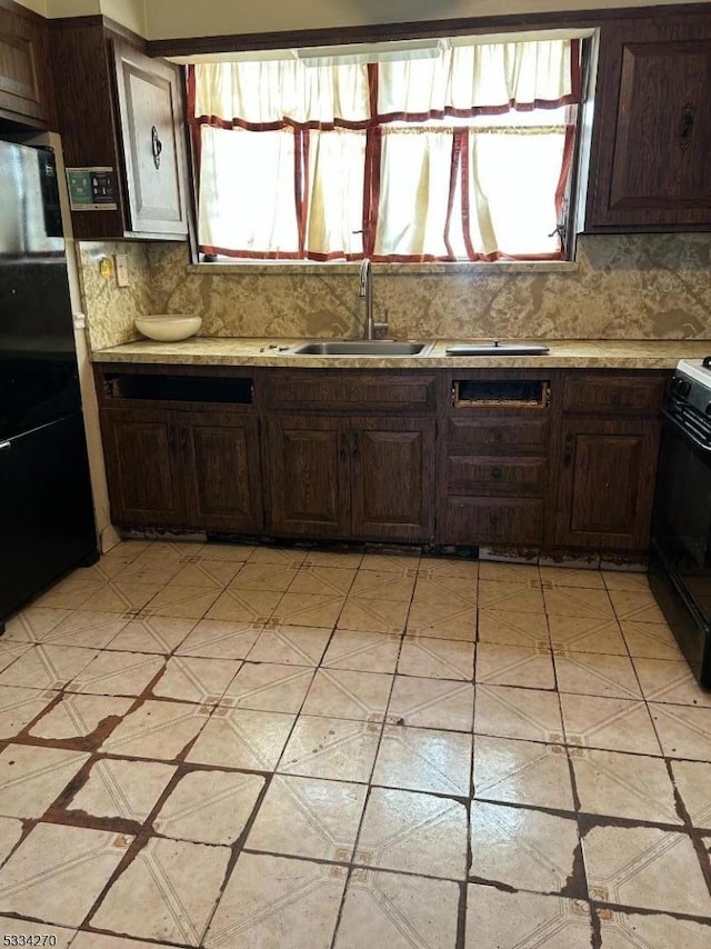 kitchen with black refrigerator, sink, decorative backsplash, electric range, and dark brown cabinets