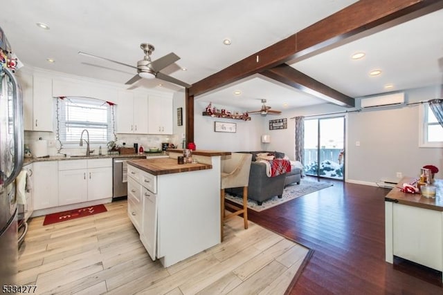 kitchen with beamed ceiling, white cabinetry, a center island, and wood counters