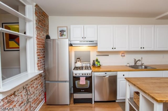 kitchen featuring butcher block countertops, sink, white cabinetry, stainless steel appliances, and light hardwood / wood-style floors