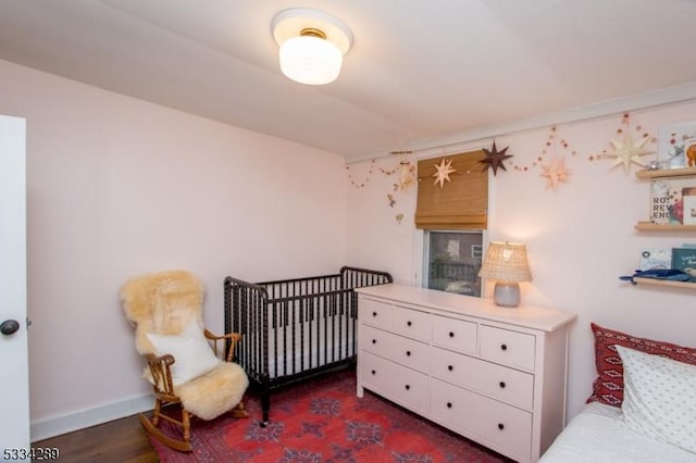 bedroom with dark hardwood / wood-style floors and a crib