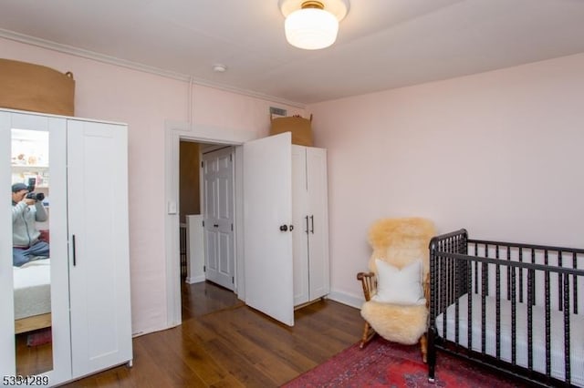 bedroom with dark hardwood / wood-style flooring and a crib