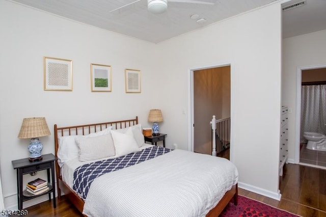 bedroom with ceiling fan, dark wood-type flooring, and ensuite bath