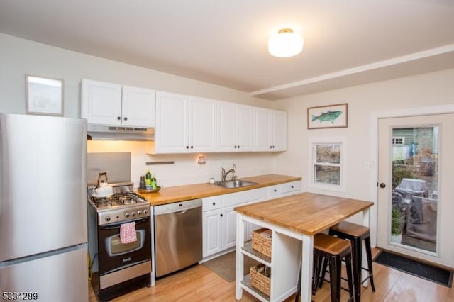 kitchen with butcher block counters, sink, a breakfast bar area, white cabinetry, and appliances with stainless steel finishes