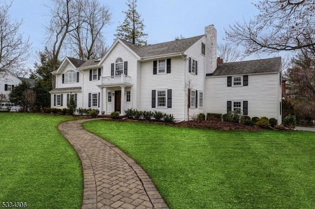 colonial house featuring a front lawn and a balcony