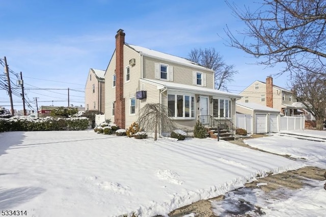 snow covered property featuring an outbuilding and a garage