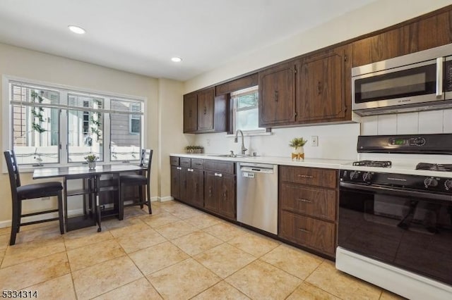 kitchen with appliances with stainless steel finishes, sink, a wealth of natural light, and light tile patterned floors