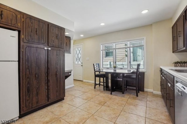 kitchen featuring dark brown cabinetry, light tile patterned floors, dishwasher, and white fridge