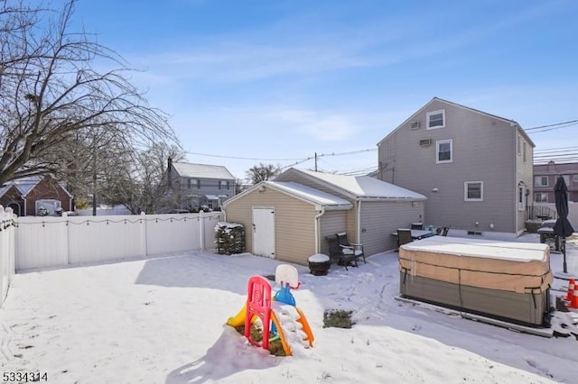 snow covered property with an outbuilding and a covered hot tub