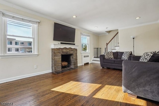 living room with ornamental molding, a stone fireplace, radiator heating unit, and dark hardwood / wood-style flooring