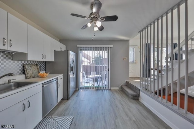 kitchen featuring sink, light hardwood / wood-style flooring, appliances with stainless steel finishes, white cabinetry, and decorative backsplash