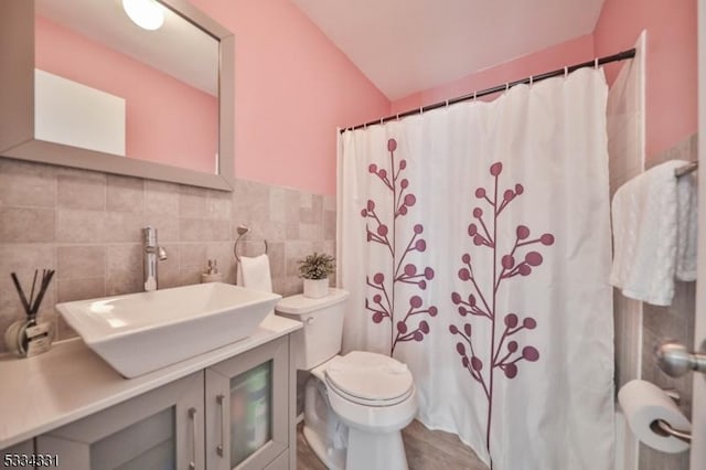 bathroom featuring walk in shower, toilet, tasteful backsplash, tile walls, and vanity