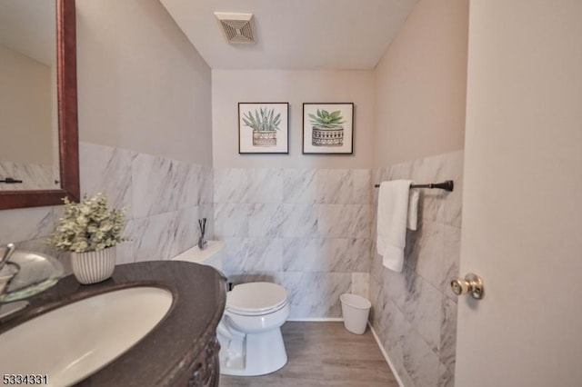 bathroom featuring hardwood / wood-style flooring, vanity, tile walls, and toilet