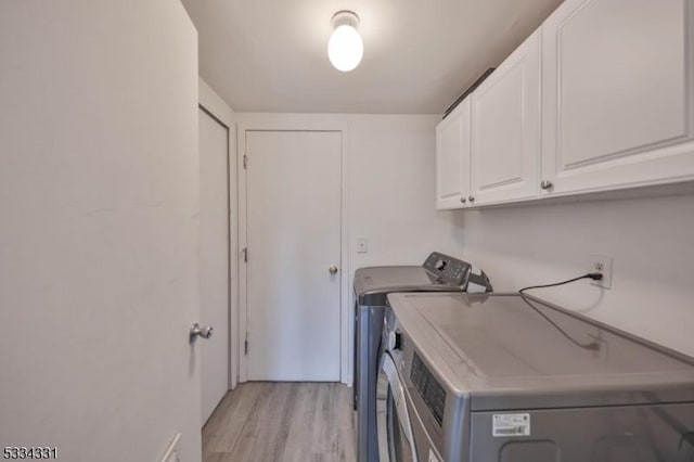 clothes washing area with cabinets, separate washer and dryer, and light wood-type flooring