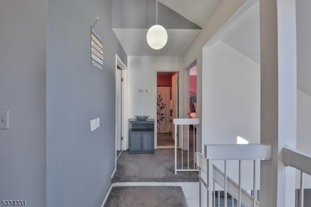 hallway featuring vaulted ceiling and dark carpet