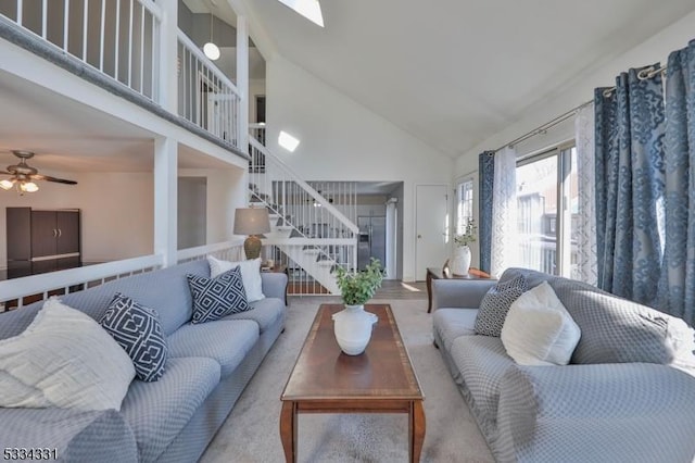 living room with ceiling fan, a skylight, and high vaulted ceiling