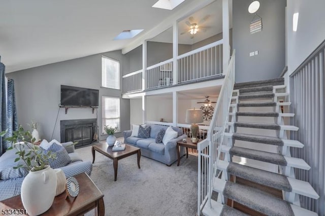 carpeted living room with beam ceiling, a skylight, high vaulted ceiling, and ceiling fan