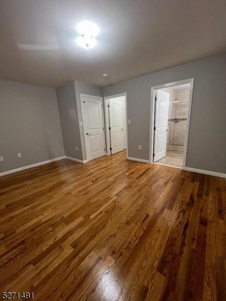 unfurnished bedroom featuring hardwood / wood-style flooring and ensuite bathroom