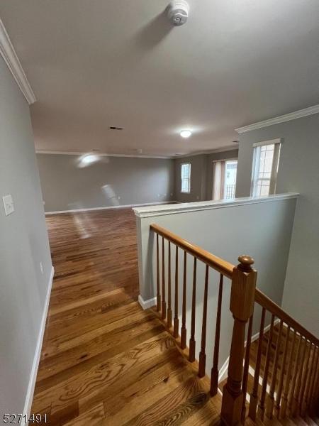 staircase featuring wood-type flooring and crown molding