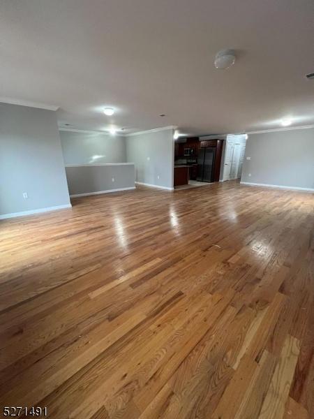 unfurnished living room featuring crown molding and light wood-type flooring