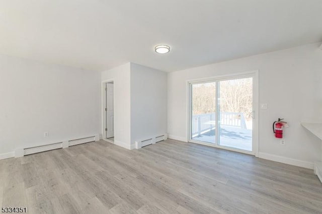 empty room featuring light wood-type flooring and a baseboard heating unit