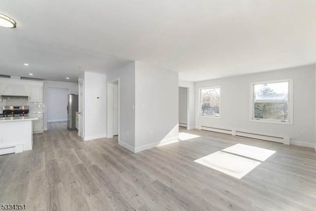 unfurnished living room with a baseboard heating unit and light hardwood / wood-style floors