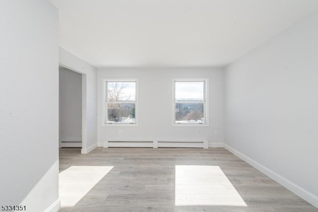 empty room with a baseboard radiator and light hardwood / wood-style floors