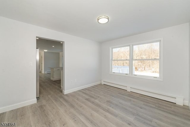 empty room featuring a baseboard radiator and light hardwood / wood-style floors