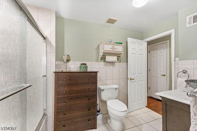 bathroom with tile patterned flooring, vanity, tile walls, and a shower with shower door