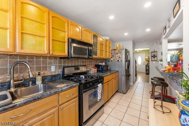 kitchen featuring tasteful backsplash, appliances with stainless steel finishes, sink, and light tile patterned floors