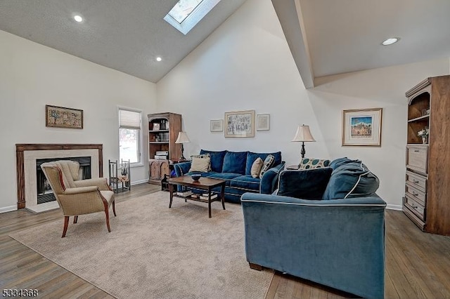 living room with hardwood / wood-style flooring, high vaulted ceiling, and a skylight