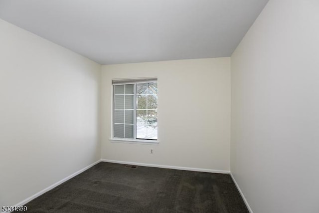 spare room featuring dark colored carpet