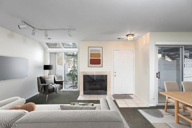 carpeted living room with a tiled fireplace and track lighting