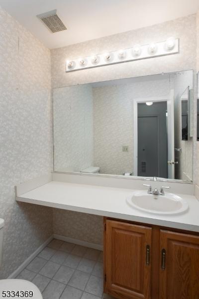 bathroom with vanity, tile patterned flooring, and toilet