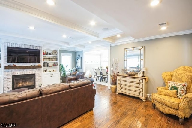 living room featuring wood-type flooring, ornamental molding, beamed ceiling, a healthy amount of sunlight, and a fireplace