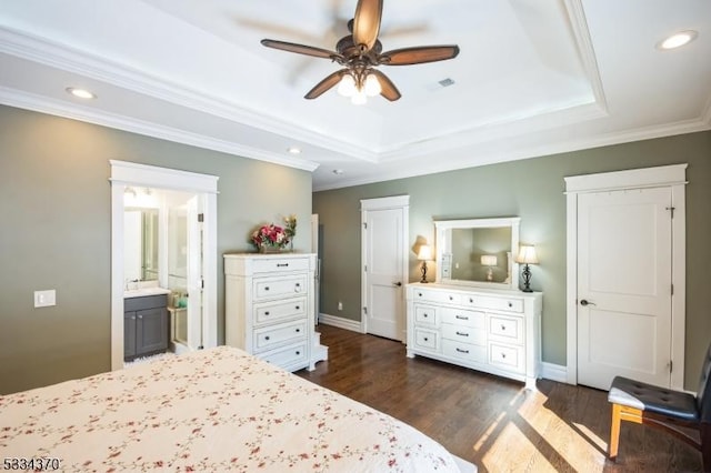 bedroom featuring a raised ceiling, ensuite bathroom, dark hardwood / wood-style flooring, and ceiling fan