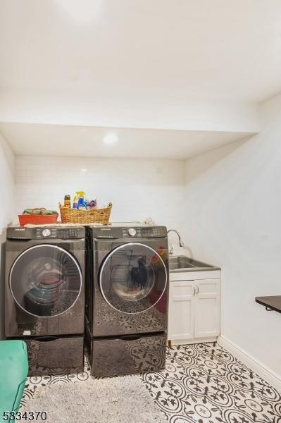 washroom featuring cabinets, washing machine and clothes dryer, sink, and light tile patterned floors